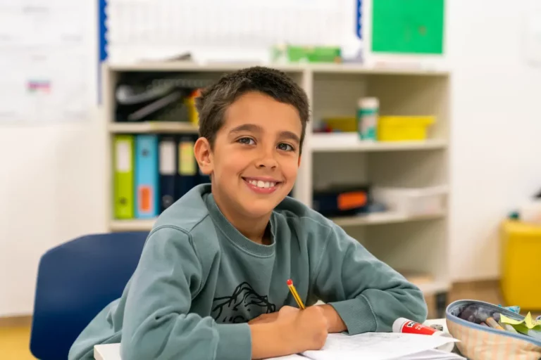 a boy sitting at a desk with a pencil and paper