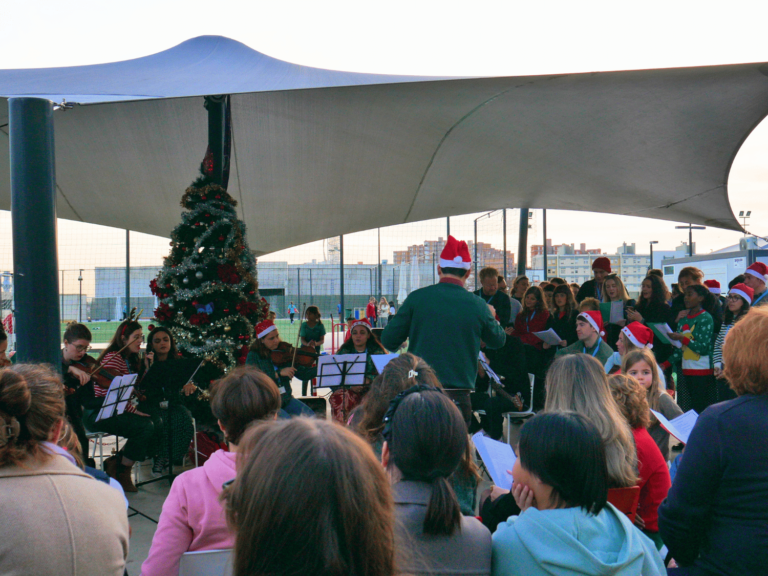 a group of people sitting under a tent with a christmas tree and a man playing music